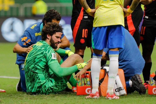 Brazil's goalkeeper #01 Alisson receives medical attention after colliding with Colombia's defender #23 Davinson Sanchez (out of frame) during the 2026 FIFA World Cup South American qualifiers football match between Brazil and Colombia, at the Mane Garrincha stadium in Brasilia, on March 20, 2025. (Photo by Sergio Lima / AFP) (Photo by SERGIO LIMA/AFP via Getty Images)